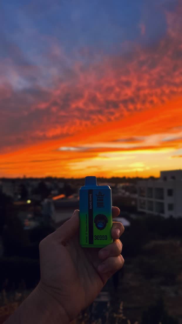 A device held up against a burning orange sunset